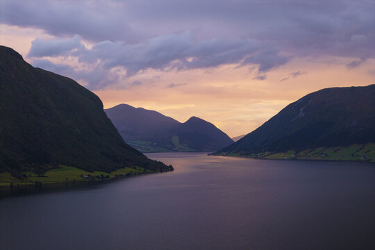 Aerial view of serene fjord waters reflecting the dusky sky between towering mountains, a tranquil vista of nature's grandeur, Skei i Jolster, Vestland, Norway.