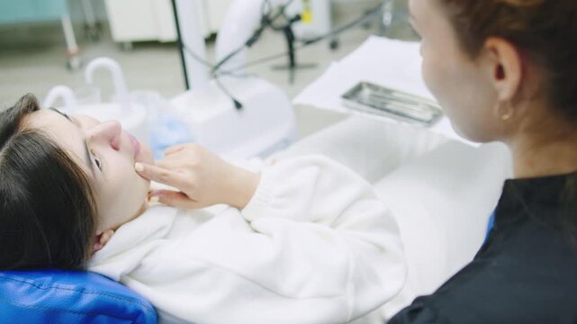 Woman consults with dentist while seated in dental chair dressed in a white robe at a dental clinic during a routine appointment