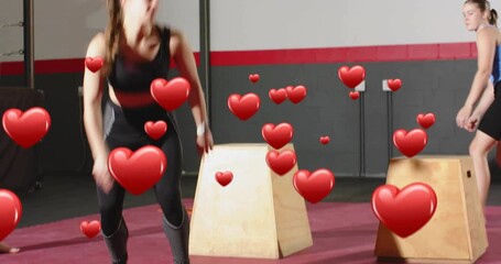 Trainer signaling, two women doing box jumps and burpees for fitness, red heart overlaying trio