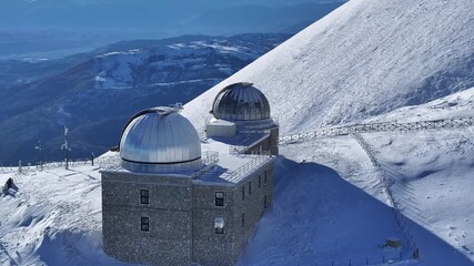 Breathtaking aerial drone footage of the Campo Imperatore Observatory high in the snowy Apennine mountains of Gran Sasso, Abruzzo, Italy on a sunny day. Cinematic 4K