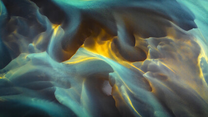 Aerial view of glacial river patterns display a mesmerizing swirl of turquoise, gold, and grey hues creating an ethereal landscape, Hvolsvollur, Rangarbing eystra, Iceland.