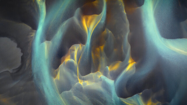 Aerial view of glacial rivers carve through the volcanic landscape, weaving a tapestry of teal and gold, Hvolsvollur, Rangarbing eystra, Iceland.