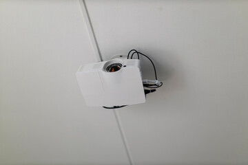 A white digital projector is mounted directly onto a tiled ceiling, showing exposed connection cables.