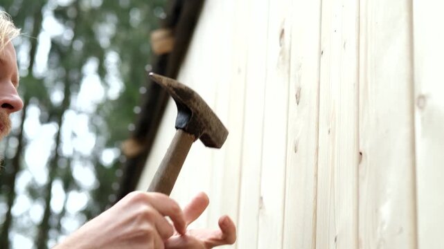 Skilled man using hammer to secure wooden panel, camera zooms in on action