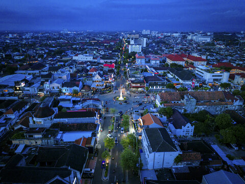 Aerial view of Tugu Jogja monument glows warmly amidst the urban sprawl under the fading twilight, Yogyakarta, Daerah Istimewa Yogyakarta, Indonesia.
