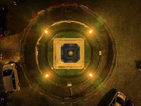 Aerial view of a gleaming Tugu Jogja monument, radiating golden light against the dark of night, a beacon in the city, Yogyakarta, Daerah Istimewa Yogyakarta, Indonesia.