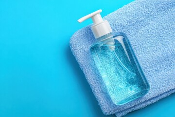 Blue liquid soap pump bottle and soft towel on cyan background