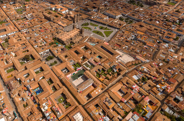 Fototapeta premium Aerial view of the dense historic center of Cusco, Peru. Features the Plaza de Armas and a geometric pattern of colonial red tile roofs and internal courtyards (patios).