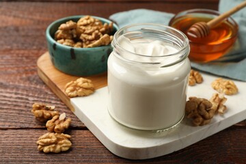 Delicious Greek yogurt with honey and walnuts served on wooden table, closeup