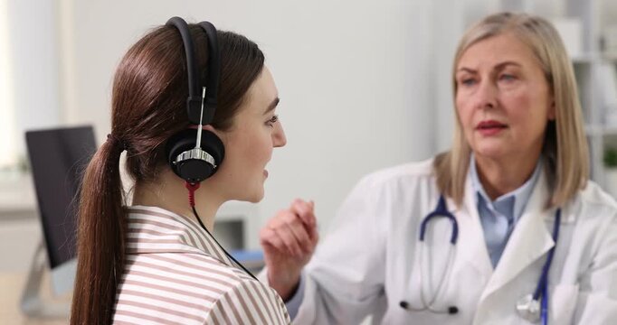 Hearing test. Doctor adjusting patient's audiometric headphones in clinic, selective focus