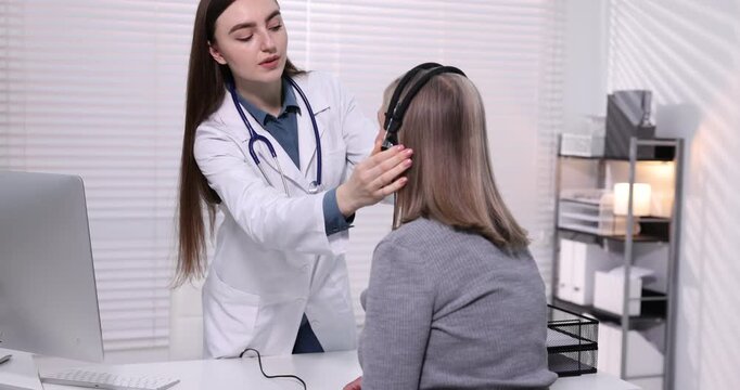 Hearing test. Doctor working with patient in audiometric headphones indoors. Camera moving up