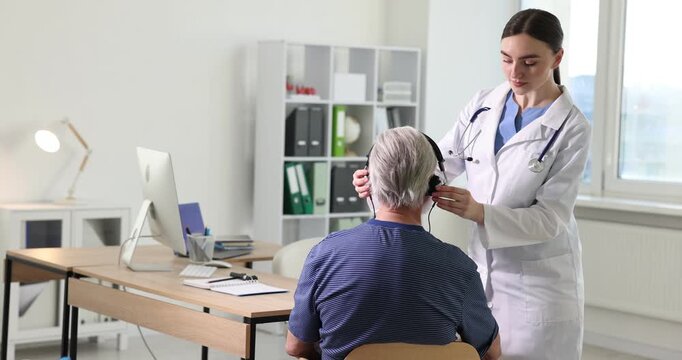 Hearing test. Doctor adjusting patient's audiometric headphones in clinic