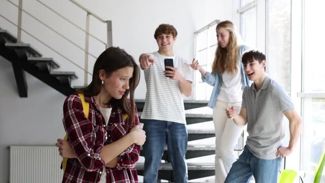 Students bullying their classmate on stairs indoors