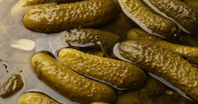 Closeup view of pickled cucumbers in brine as background, spinning
