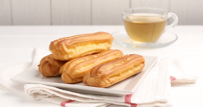 Woman taking tasty eclair from white table, closeup