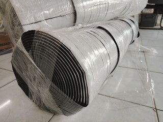 Warehouse stock of flexible, insulating black foam rubber rolls, specifically designed for...