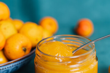 Yellow fruit jam in jar with spoon