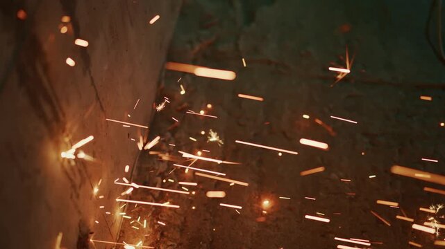 sparks dancing along concrete corner at night, scattered orange embers sweeping across textured masonry, cinematic low light, abstract industrial closeup of flying particles