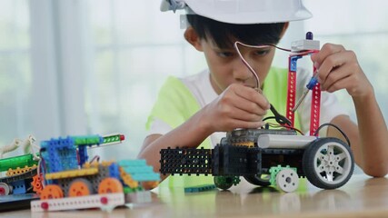 Asian boy engineer working on robotics project in a STEM education class. child is focused on assembling and learning about a small robot or electronic project. engineering, innovation, technology. - Powered by Adobe