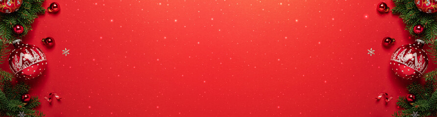 Frame of Christmas tree branches with red glitter decorations on red background. Merry Christmas and Happy New Year greeting card. Xmas and winter holidays,  top view, wide banner