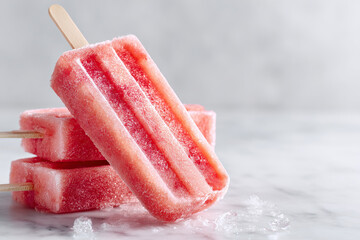Refreshing pink fruit flavored popsicles on a marble surface