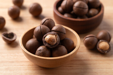 Macadamia nuts in a bowl on wooden background