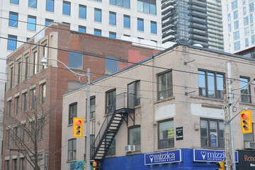 Fototapeta premium contrast of old and new buildings incl sign outside Mizzica Gelateria & Cafe, an ice cream shop, located at 307 Queen St W, Toronto