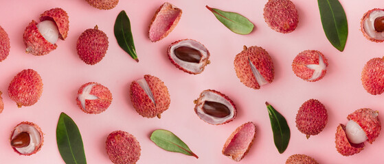 Tasty litchi fruit and leaves on pink background