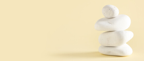 Stack of pebbles on beige background with space for text. Zen concept