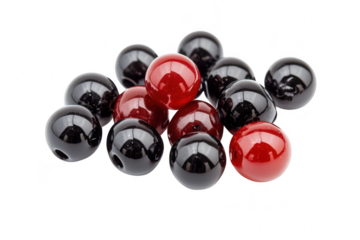 A collection of glossy black and red beads scattered artistically on a white background. their shine and color contrast. ideal for crafting and jewelry design projects
