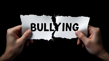 Two hands tear apart a paper with the word "bullying," symbolizing rejection of violence and support for kindness. Close-up shot with dark background and clear focus