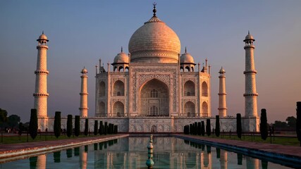 Majestic front view of the Taj Mahal at sunset, capturing its reflection in the water. Ideal for a travel video showcasing architectural beauty. Live desktop wallpaper.