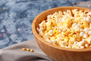 Bowl with tasty popcorn on blue background