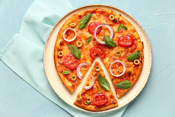 Plate with tasty pizza and towel on blue background