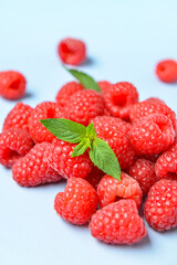 Heap of fresh raspberries and mint on blue background