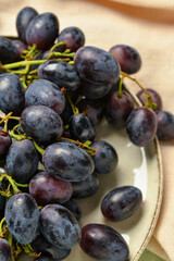 Plate with sweet black grapes on table, closeup