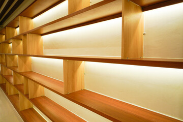 Modern wooden shelves with warm built-in lighting in a minimalist interior space