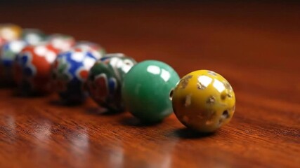 Decorative Ceramic Beads Rolling on a Polished Wooden Surface