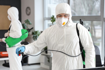 Male worker disinfecting in office