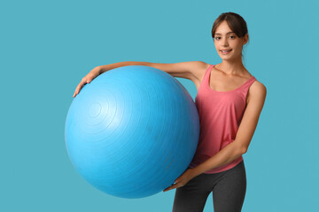 Young woman with fitball on  blue background