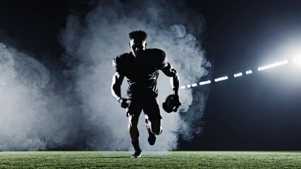 Dynamic low-angle shot of a football player running through smoke on a field, illuminated by bright lights, ideal for sports video content. - Powered by Adobe