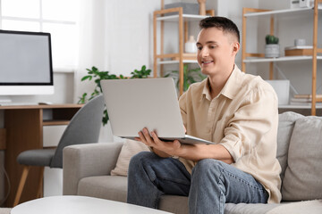 Young man using laptop on sofa at home