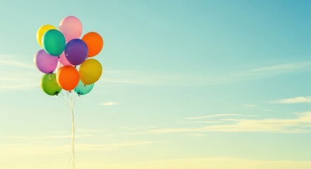 A vibrant bunch of colorful helium balloons floating against a bright, clear blue sky with soft clouds, suggesting celebration, freedom, and joy on a sunny day