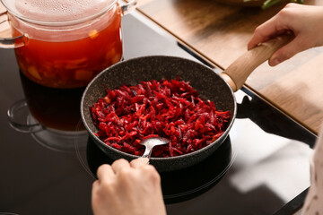 Young woman frying vegetables for delicious borscht in kitchen, closeup
