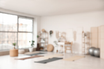 Blurred view of yoga studio with table, shelf units and mats