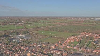Aerial view capturing a sprawling urban landscape with houses and industrial buildings juxtaposed against green fields and woodlands, bisected by a busy motorway in South Yorkshire, England