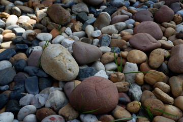 Calm and peaceful collection of natural pebbles and stones on ground. This textured background shows variety of smooth, colorful rocks creating an earthy pattern