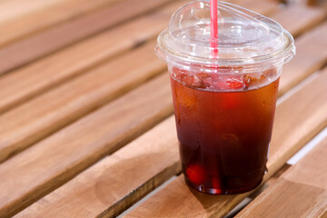 Refreshing iced tea with goji berry in plastic cup with straw on wooden table. healthy, cool, and delicious beverage perfect for summer day at cafe
