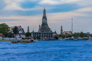 Naklejka premium 26 November 2025 Beautiful Sunset colours of Thai Temple Wat Arun on Chao Phraya River in BKK Bangkok Thailand. The magic colourful neon light display on the temple at sunset is magical.