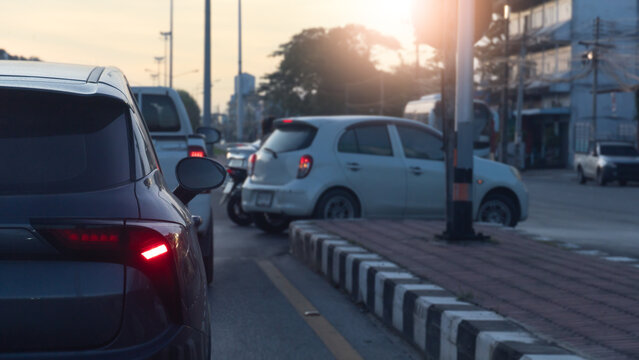 Rear side of car with turn on brake light. Waiting in line to make a U-turn in front. A blurry image of a white car making a U turn. Blurred of city and sunlight on the sky.